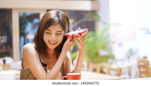 Young woman listen to voicemail in coffee shop