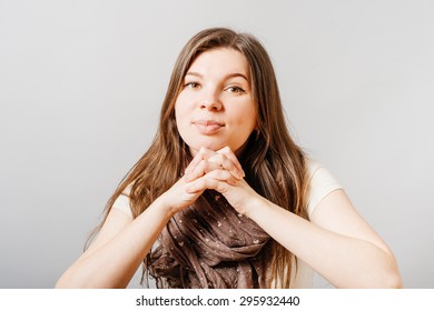 Young Woman Listening Intently. On A Gray Background.