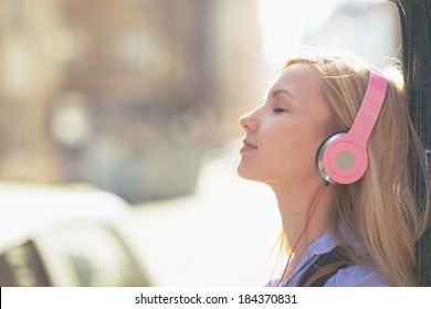 Young woman listening music in headphones in the city - Powered by Shutterstock