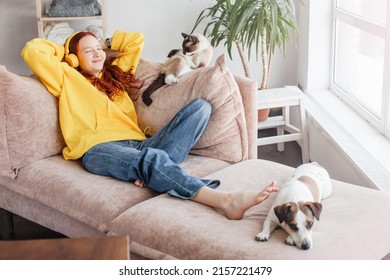 Young Woman listening music in headphones, Teen girl lying on sofa with cat and dog in living room at home
 - Powered by Shutterstock