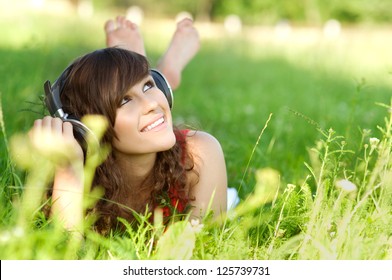 Young Woman Listening Music On Grass