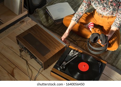 Young Woman Listening A Music On A HiFi System With Turntable, Amplifier, Headphones And Lp Vinyl Records In A Listening Room