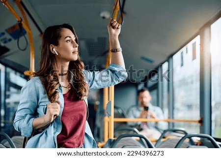 Young woman listening music over earbuds while commuting by city bus. Copy space.