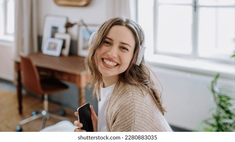 Young woman listening music trough headphones in her apartment. - Powered by Shutterstock