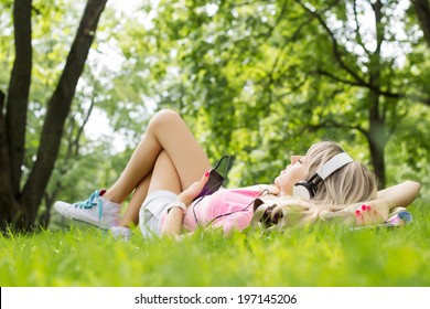 Young woman listening to music while lying down on grass