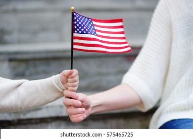 Young woman and little child holding american flag. Independence Day concept. Family together