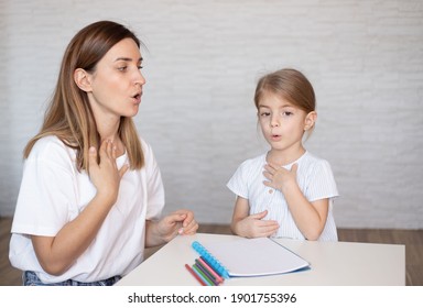 Young woman and little girl doing exercise for restructuring oral muscular phonetic targets.