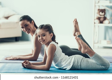 Young Woman and Little Girl Resting after Exercise. Beautiful Young Mother and Adorable Little Daughter Lying on Yoga mat. Mother and Daughter Together at Home. Healthy Lifestyle