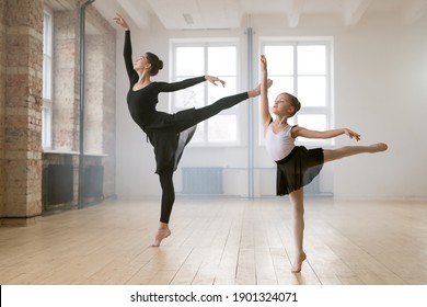 Young Woman And Little Girl Standing Together In The Same Ballet Pose And Dancing In Dance Studio