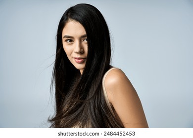 A young woman with long, black hair poses against a light grey background. - Powered by Shutterstock