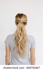 A Young Woman With Long Blond Wavy Hair Tied In A Ponytail Back View