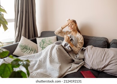 Young Woman With Long Covid Syndrome Symptoms Sitting At Couch At Home Biophilic Interior, Many Indoor Trees	