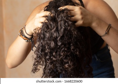 Young Woman With Long Curly Hair Giving Herself A Scalp Massage As Part Of Her Haircare Routine