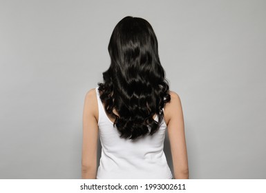 Young Woman With Long Curly Hair On Grey Background, Back View