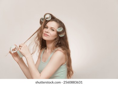 
A young woman with long curly hair styles her hair with green velcro rollers, smiling softly. The concept emphasizes self-care, natural beauty, and personal grooming, reflecting confidence femininity - Powered by Shutterstock