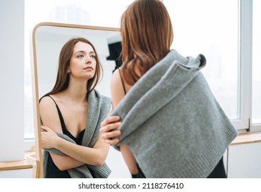 Young Woman With Long Dark Hair On Evening Elegant Black Dress With Open Back Near Mirror In The White Interior, People From Behind