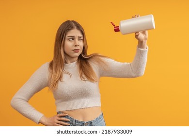 A Young Woman With Long Hair Looks With One Eye Into An Open Bottle, Find Out If The Shampoo Is Over Or Not, Color Background