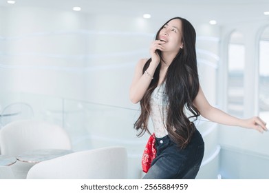 A young woman with long hair smiles joyfully in a stylish indoor space. The modern decor and soft lighting enhance her playful and carefree attitude, creating a serene and vibrant atmosphere. - Powered by Shutterstock