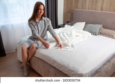 Young Woman With Long Red Hair Is Sitting On Bed And Folding Clean White Hand Towels Into Mesh Basket In Bedroom. Stack Of Roll Up Towels With Copy Space. Neat And Tidy Linen. Hypoallergenic Textile.