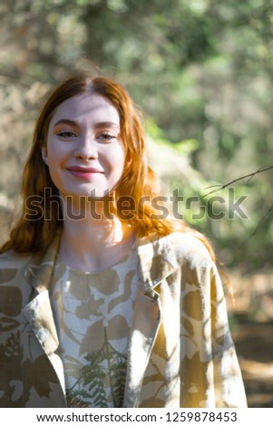 Young woman with long red hair in a linen dress gathering mushrooms in the forest in the bast basket