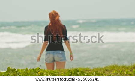 Young woman with long red hair on caribbean beach, Dominican Republic, rear view