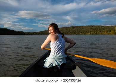 Young woman looking back and smiling in a canoe on Lake Sequoyah in Fayetteville, Arkansas.