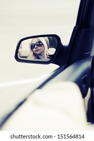 Young Woman Looking In The Car Mirror