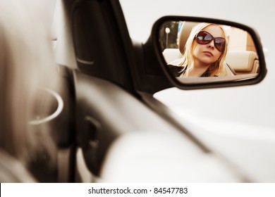 Young Woman Looking In The Car Mirror