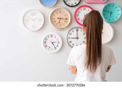 Young Woman Looking At Different Clocks