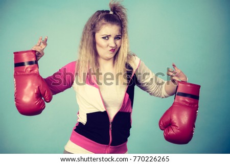 Young woman looking with disgust at boxing glove, she does not like fighting and aggression