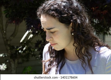 Young Woman Looking Down, Furrowed Brow, Bright Sunlight, Horizontal Aspect