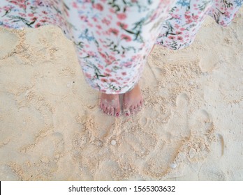 Young Woman Looking Down Point Of View Perspective On Bare Feet Standing In Yellow Sand In Greece.