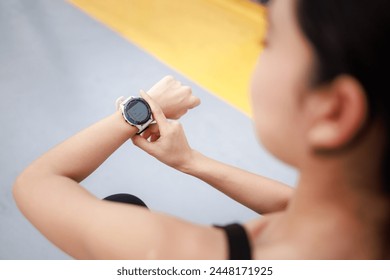 young woman looking down at the timer on her wrist to time before jogging in the morning. - Powered by Shutterstock