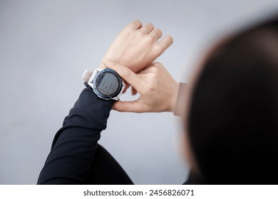 young woman looking down at the timer on her wrist to time before jogging in the morning. - Powered by Shutterstock