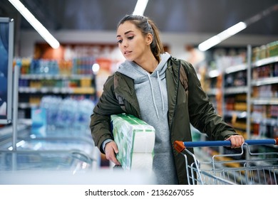 Young woman looking at freezer while buying groceries at supermarket.  - Shutterstock ID 2136267055