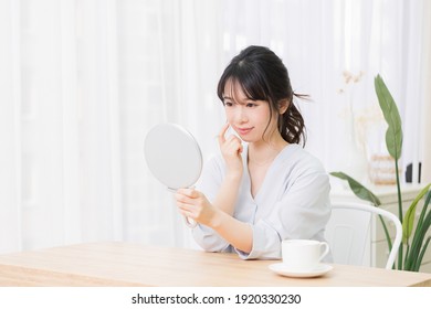 Young Woman Looking In A Hand Mirror In The Room