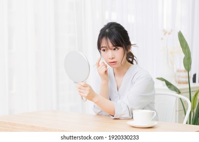 Young Woman Looking In A Hand Mirror In The Room