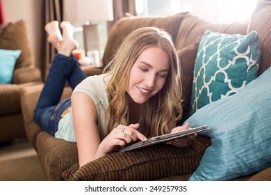 Young Woman Looking At Her Tablet On The Couch