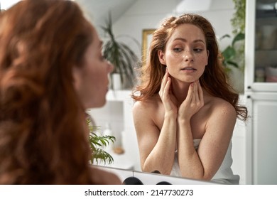 Young woman looking at herself in the mirror in the morning  
