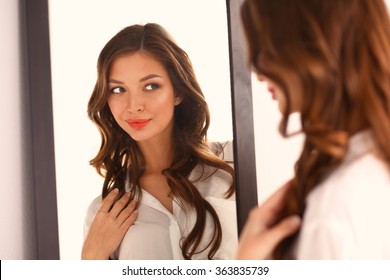 Young Woman Looking Herself Reflection In Mirror At Home