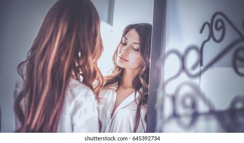 Young woman looking herself reflection in mirror at home - Shutterstock ID 645392734