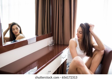 Young woman looking herself reflection in mirror