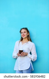 Young woman looking up holding cup coffee