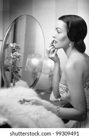 Young woman looking into a mirror and putting on make up