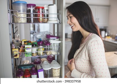 Young Woman Looking Into The Storage Cabinet In Kitchen