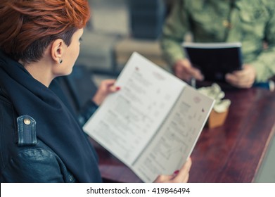 Young Woman Looking At The Menu In A Restaurant. Close Up