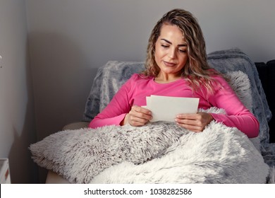 Young Woman Looking At Old Family Photographs
