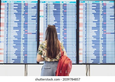 Young Woman Looking On The Timetable Schedule List Before The Flight In Airport 