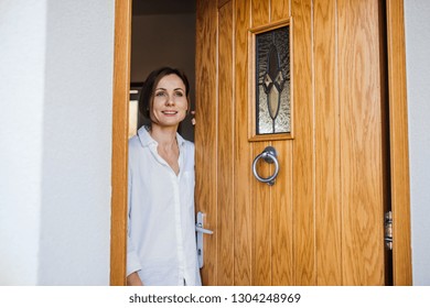 A Young Woman Looking Out Of Front Door. Copy Space.