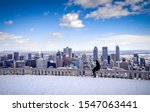 Young woman looking out over downtown Montreal from a snow-covered observation area in Mount Royal Park - Montreal, Canada (Winter) 